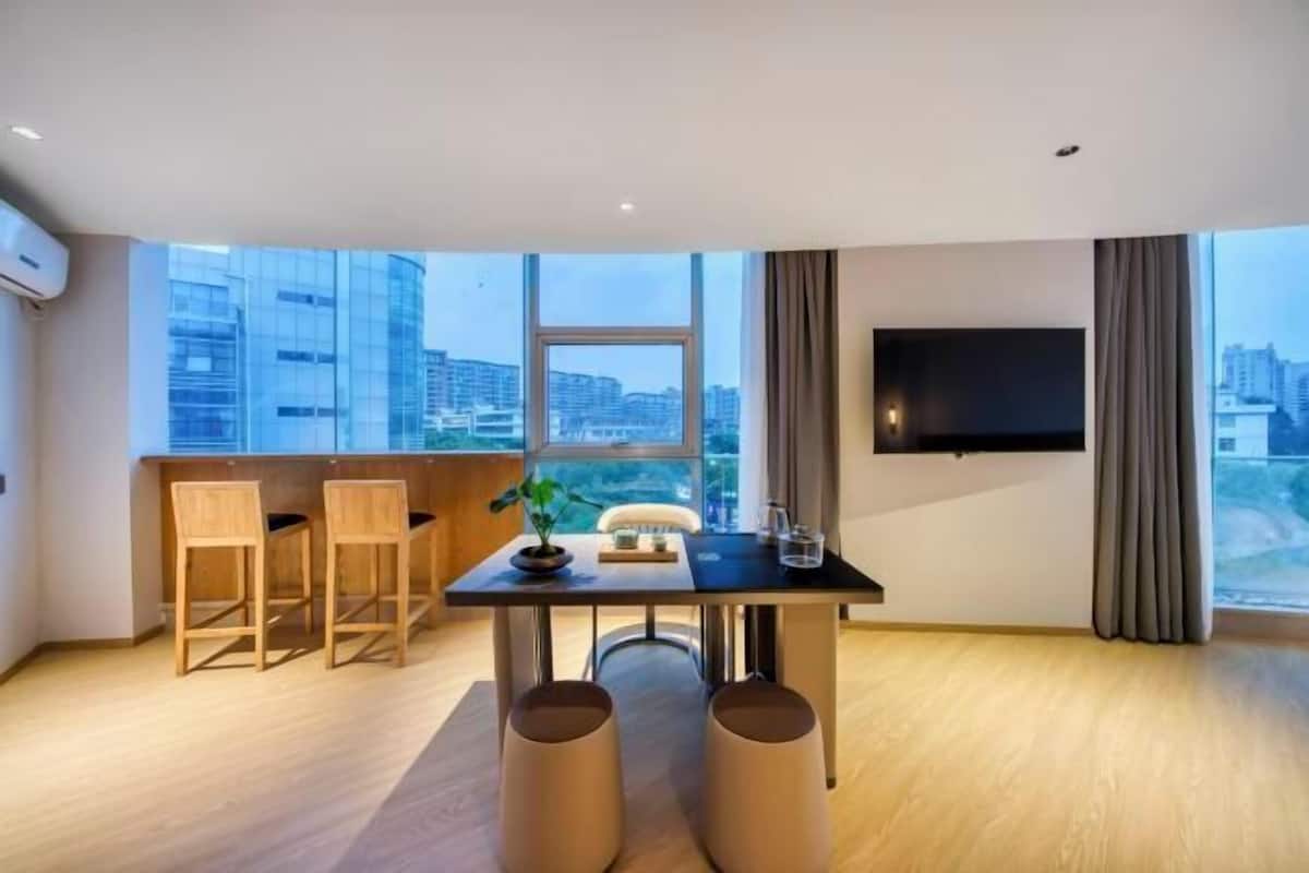 Ein modernes Wohnzimmer mit Essbereich, großen Fenstern, einem Flachbildfernseher und Blick auf die Stadt.