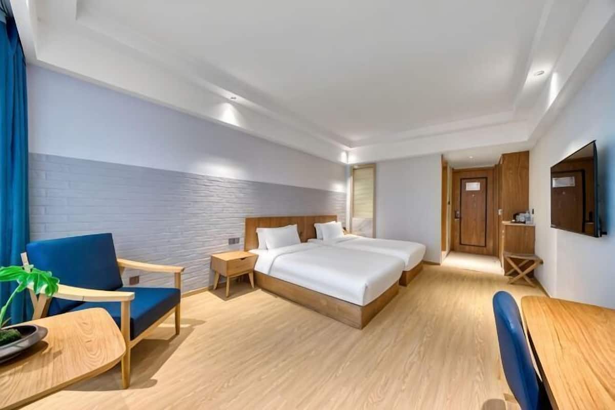 Ein Hotelzimmer mit einem großen Bett, einem Schreibtisch, einem Stuhl und einem Fernseher.