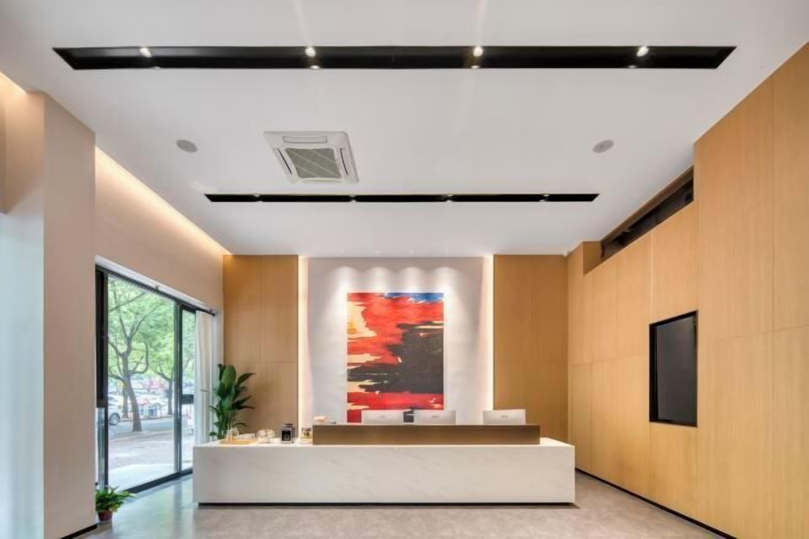 A modern reception area with a reception desk, a large abstract painting, and a large window providing a view of the outdoors.