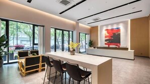 A modern interior with a long white counter, black chairs, and large windows offering a view of the outdoors. - Hotel Jagri Taizhou (Taizhou)