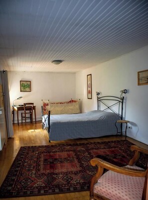 Une chambre à coucher avec un lit, un bureau, une chaise et un tapis à motifs.