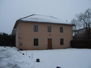 Un edificio a due piani con facciata simmetrica, ingresso centrale e tetto innevato.