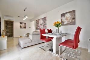 A modern dining area with a white table, red chairs, and a vase of flowers.