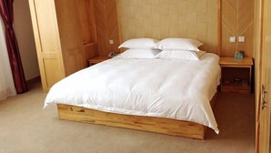 A wooden bed with white bedding in a room with wooden walls and a carpeted floor. - Yunti Hotel (Jinping)