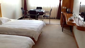 Une chambre d’hôtel avec deux lits, un bureau, une chaise, une télévision et une fenêtre avec des rideaux.