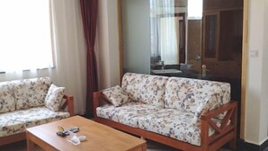 A living room with two sofas, a coffee table, and a large mirror. - Yunti Hotel (Jinping)