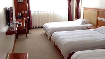 Une chambre d’hôtel avec deux lits, un bureau, une chaise, une télévision et une fenêtre avec des rideaux.