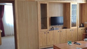 A wooden cabinet with a television, a small table, and a chair. - Yunti Hotel (Jinping)
