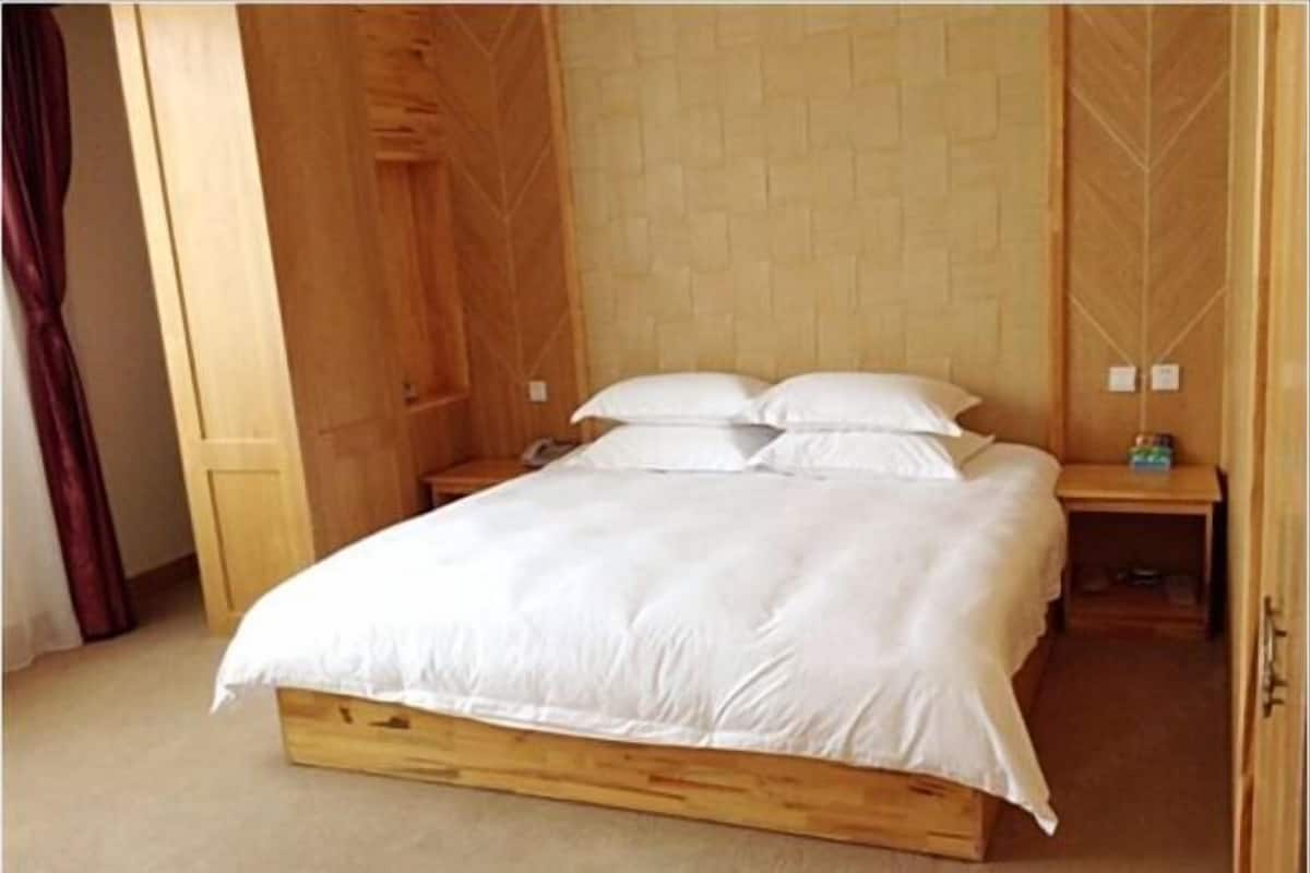 A wooden bed with white bedding in a room with wooden walls and a wooden door.