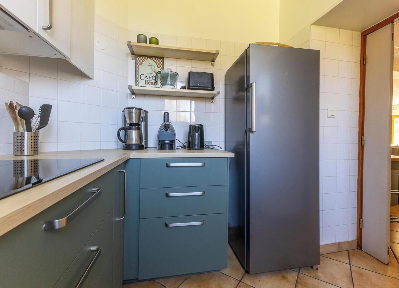 A compact kitchen with a refrigerator, a coffee maker, and a toaster on the countertop.