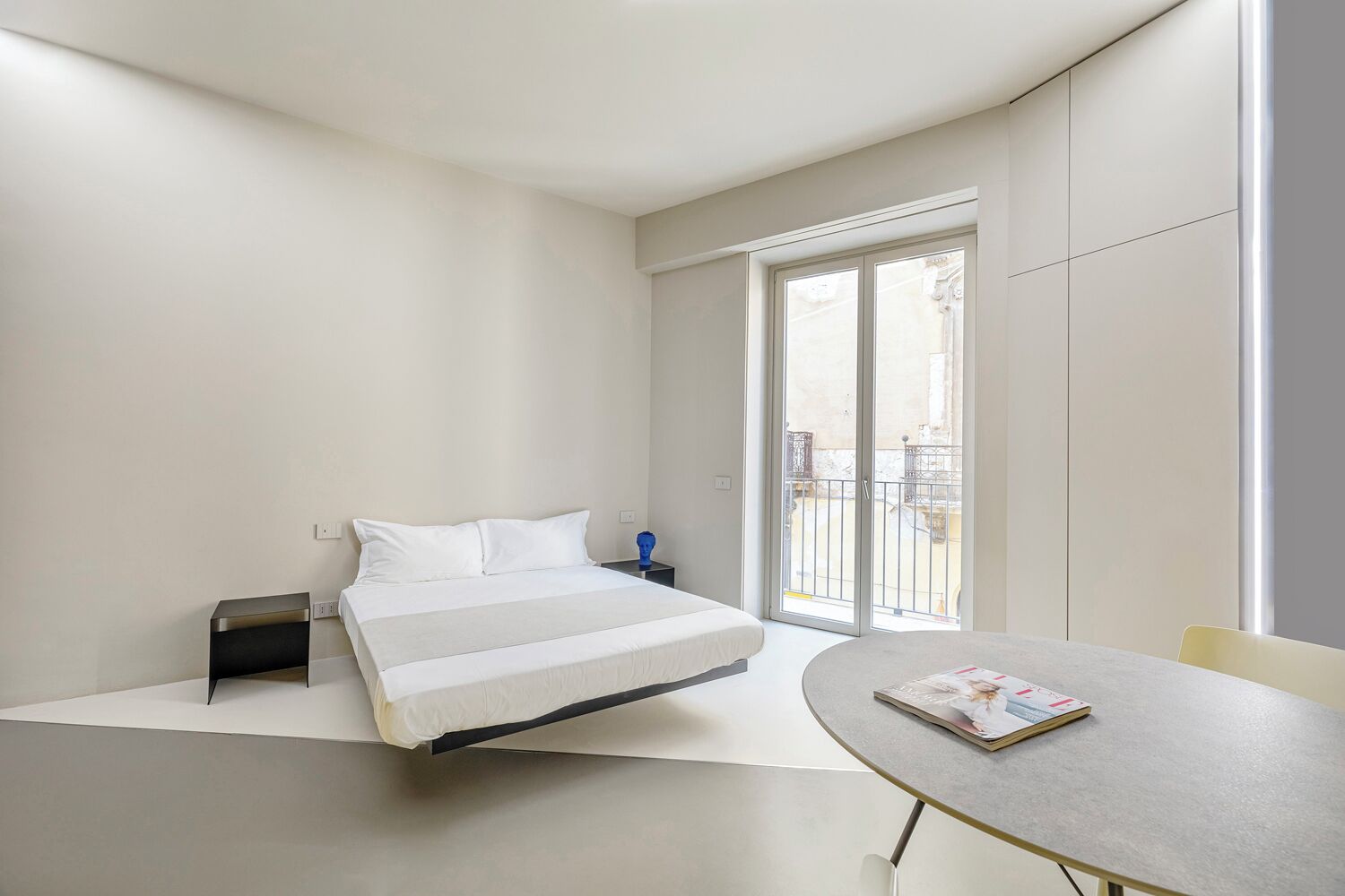 A modern bedroom with a bed, bedside table, and a table with a magazine.