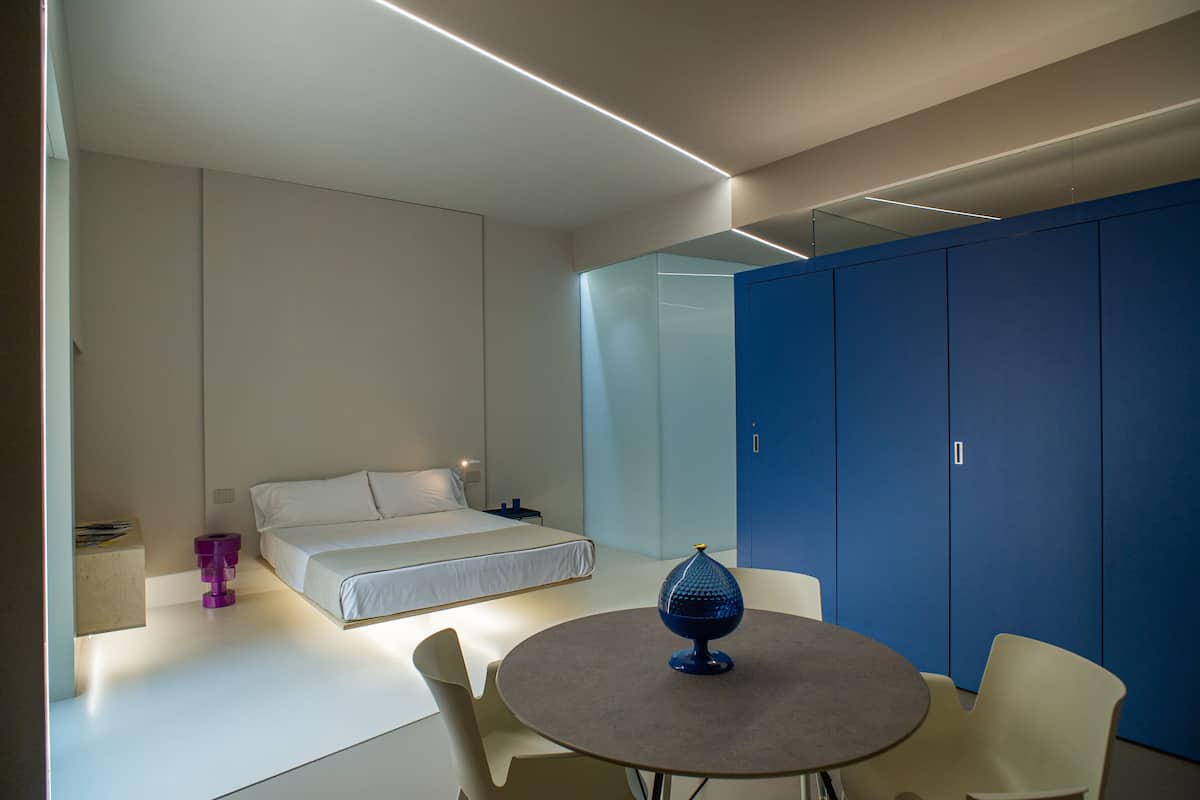 A modern bedroom with a bed, a round table, and a blue wardrobe.