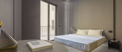 A modern bedroom with a bed, a bedside table, a book, and a window.