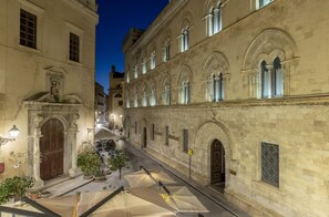 A historic building with arched windows and a courtyard with potted plants and umbrellas. - Fiveplace Design Suite & Apartments (Trapani)