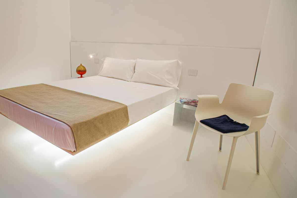 A minimalist bedroom with a bed, a chair, and a small table.