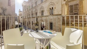 A balcony with a table, two chairs, a bottle of wine, and a glass of wine. - Fiveplace Design Suite & Apartments (Trapani)