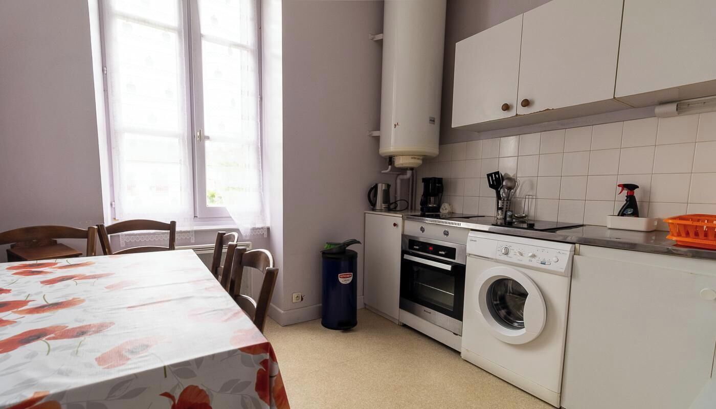 A compact kitchen with a washing machine, oven, and a coffee maker.