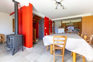 Cozy living space with a wood-burning stove, dining area, and staircase to an upper level.