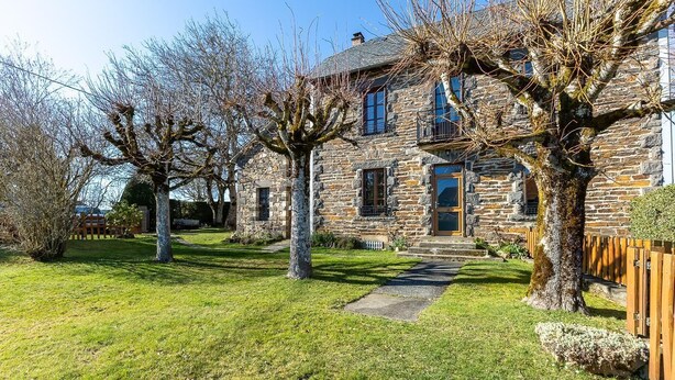 A stone house with a stone facade, a wooden door, and a paved driveway.