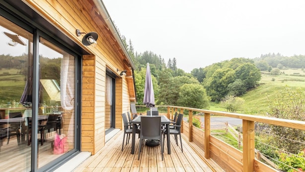 Une terrasse en bois avec des meubles d’extérieur, une table à manger et des chaises.