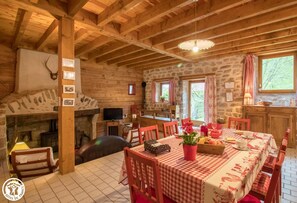 Cozy living area with a stone fireplace, dining table, and potted plant.