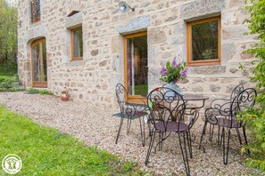 Traditional stone building with a charming patio area, featuring a small table and chairs for outdoor dining.