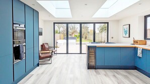 Una cocina moderna con una isla central, horno integrado y una zona de comedor con una silla.