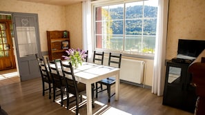 Enjoy a serene lake view from the comfort of this cozy room, featuring a dining table, bookshelf, and TV.