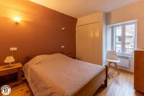 Relax in this serene bedroom with a large bed, nightstand, and window offering a view of the outside.