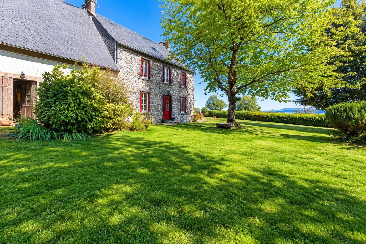 A stone house with a red door and a well-maintained lawn.