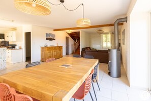Un comedor amplio con una mesa y sillas de madera, una cocina con armarios blancos y una escalera que lleva a otro nivel.