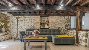 Un salon chaleureux avec des murs en pierre, un canapé gris, une table basse en bois et un lampadaire.