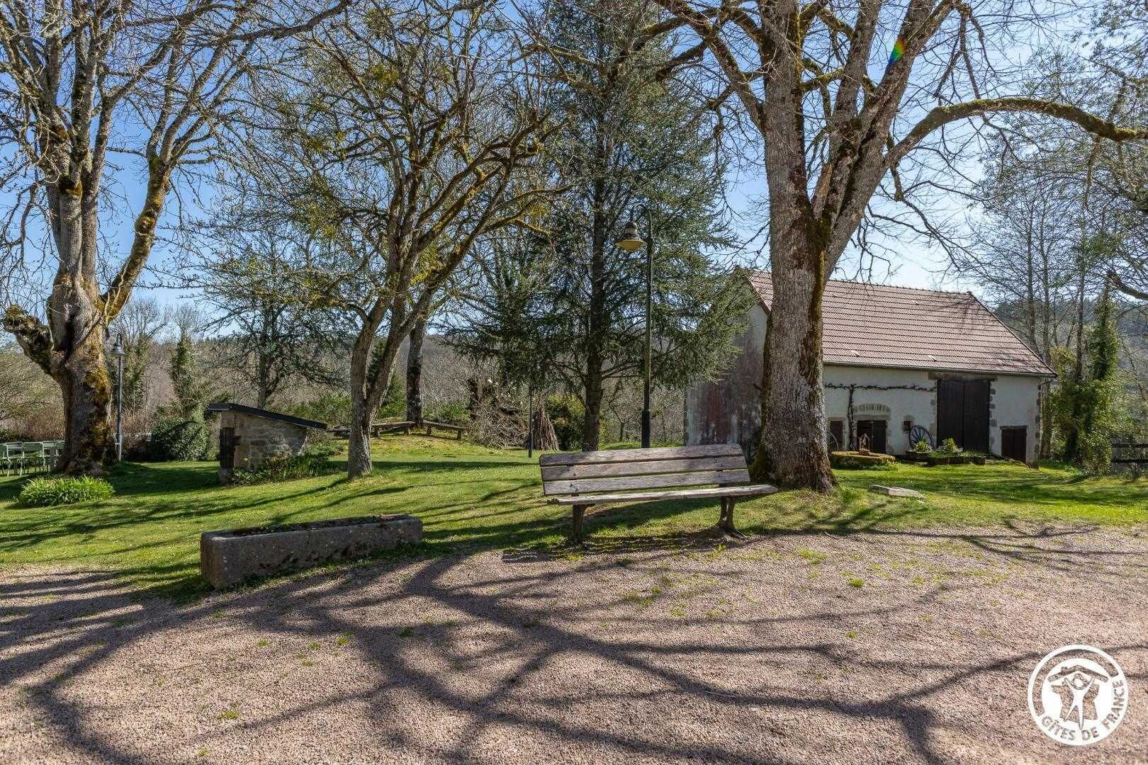 A rustic building with a gravel path, a wooden bench, and a stone wall.