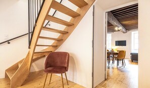 A staircase with wooden steps and metal railings, leading to a dining area with a table and chairs.