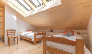 A room with two wooden bunk beds, a wooden chair, and skylights.