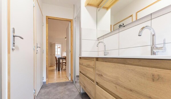 A narrow hallway leading to a dining area with a wooden floor and white walls.