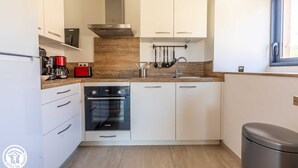 Una cocina moderna con armarios blancos, un horno Bosch, una cafetera roja y un ventanal con vistas.