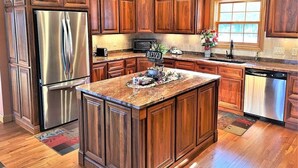 Une cuisine dotée de meubles en bois, d’appareils électroménagers en acier inoxydable et d’un îlot central.
