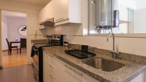 A modern kitchen with white cabinets, a granite countertop, a stainless steel sink, and a built-in oven.