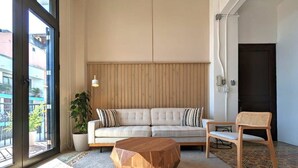 Un salón con sofá, mesa de centro de madera, sillón y planta en maceta.