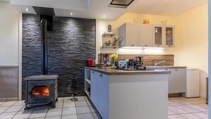 Una cocina moderna con una isla central, estufa integrada, armarios grises y una pared de acento de piedra.