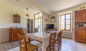 Un comedor con mesa, sillas, televisor y armarios de madera.