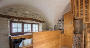 Uma cozinha rústica com bancada de madeira, janela com vista e parede de pedra.