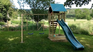 Une aire de jeux en bois avec des balançoires et un toboggan.
