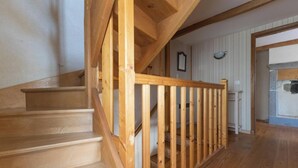 A wooden staircase with a railing leading to a room with a stone fireplace. - La Salamandre - Saint-victor-la-riviere (SAINT-VICTOR-LA-RIVIERE)