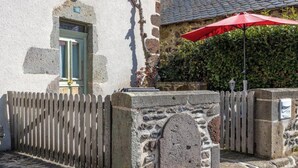 A stone building with a wooden picket fence, a red umbrella, and a stone wall with a circular window. - La Salamandre - Saint-victor-la-riviere (SAINT-VICTOR-LA-RIVIERE)