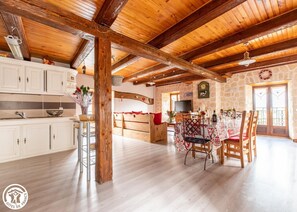 Experience a warm and inviting space with exposed beams, a modern kitchen, and a dining area perfect for communal meals.