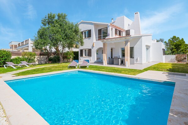 Une maison moderne à deux étages, dotée d’une piscine, de mobilier d’extérieur et d’une pelouse bien entretenue.