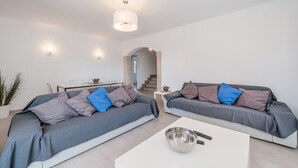 A modern living room with two grey sofas, a white coffee table, and a staircase leading to another room.