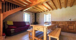 Une pièce chaleureuse avec un plafond en bois, un mur en pierre, une table en bois, un banc et un canapé.
